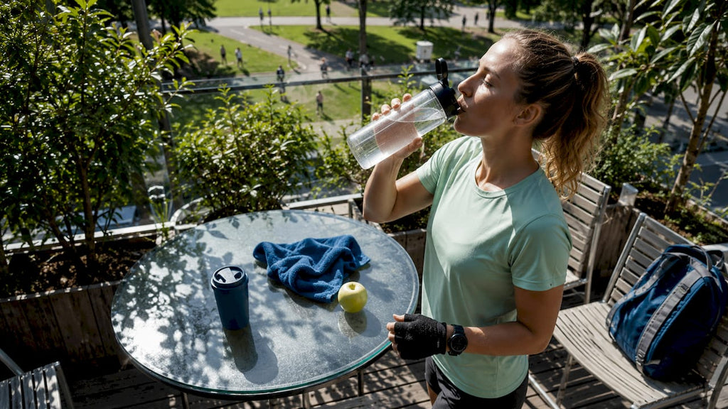 Een sportieve vrouw geniet van een suikervrije dorstlesser in het park.