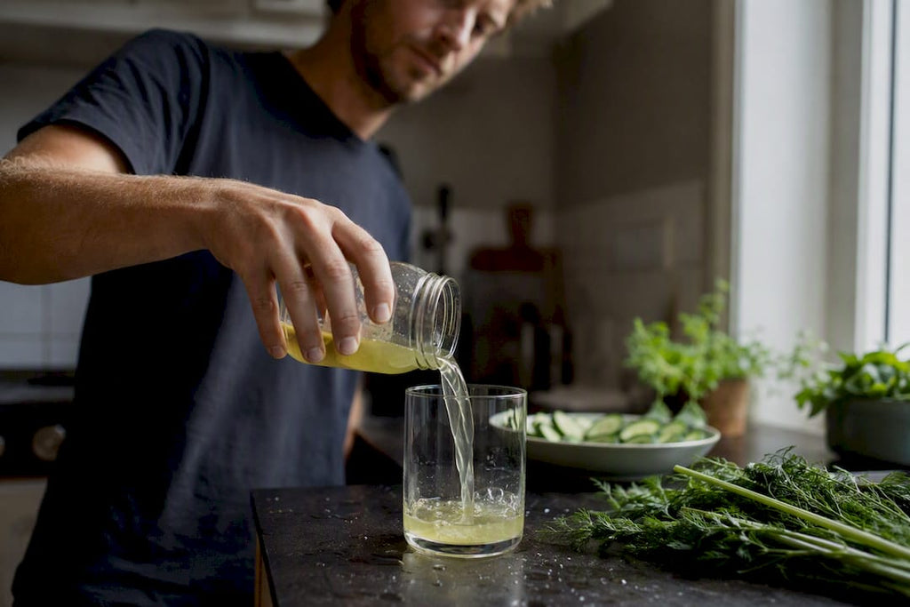 Man die augurkenvocht in een glas schenkt