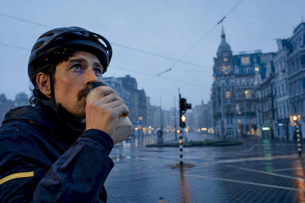 Stedelijke fietser neemt slokje tijdens vroege rit